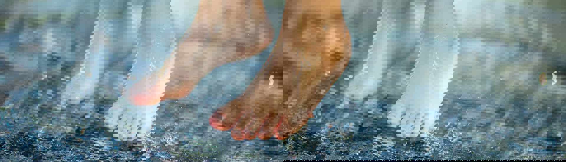 Kind springt blootvoets in de plassen