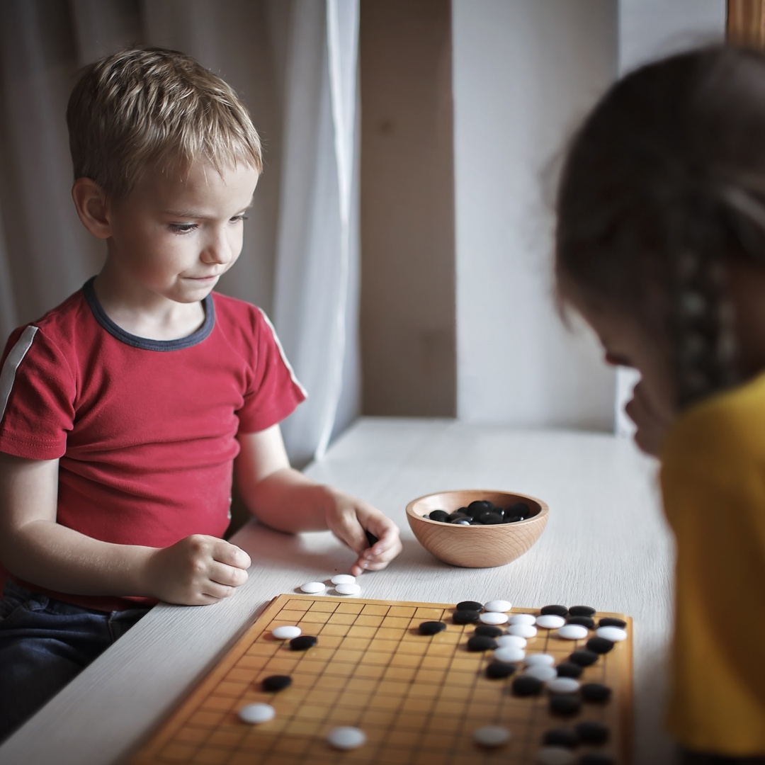 Jongen en meisje spelen gezelschapsspelletje: kind kan niet tegen verlies