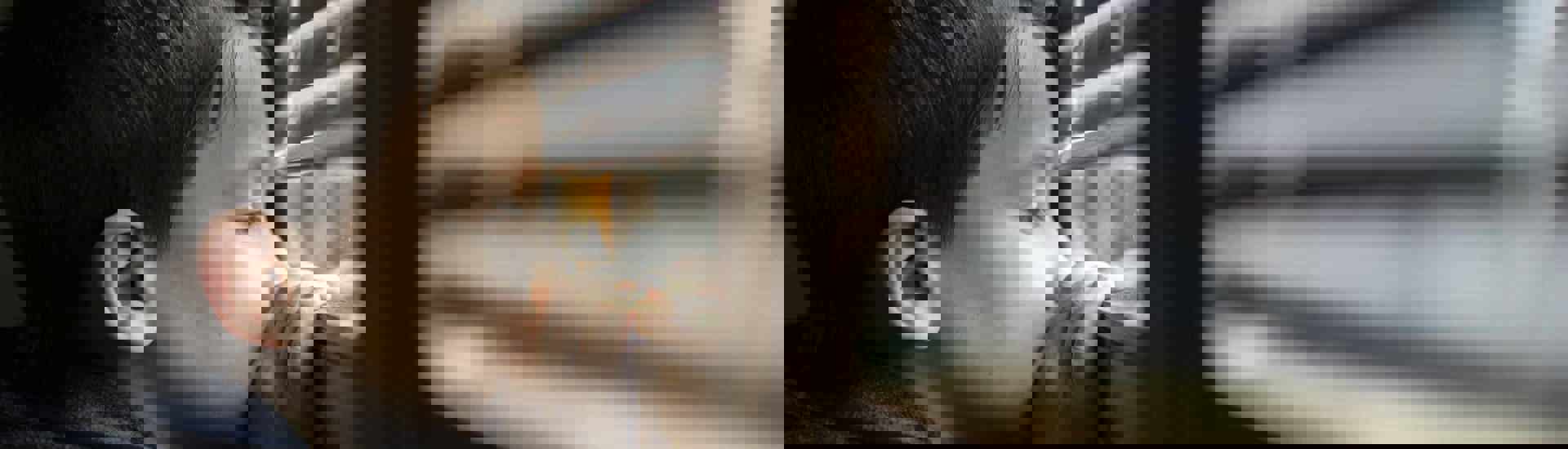 Rouwend kind kijkt door de kieren van een rolluik: zo help je kinderen bij verlies