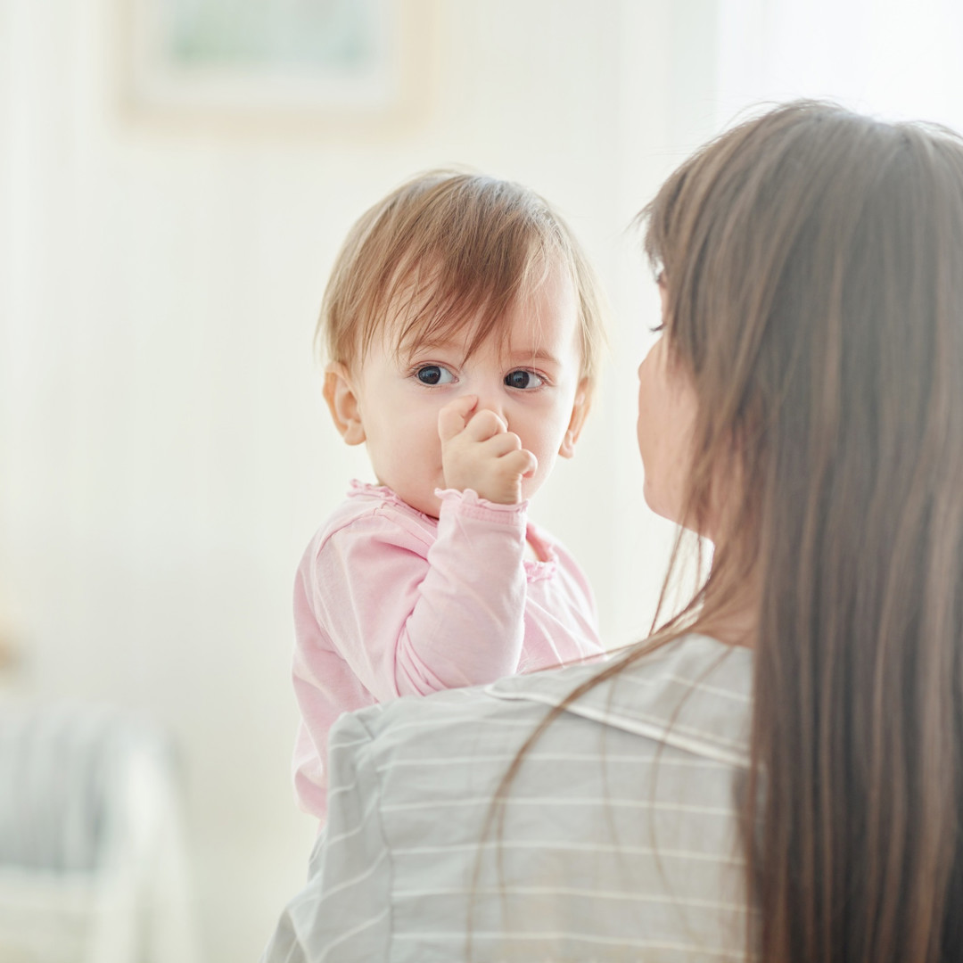 duimzuigend kind op schouder mama