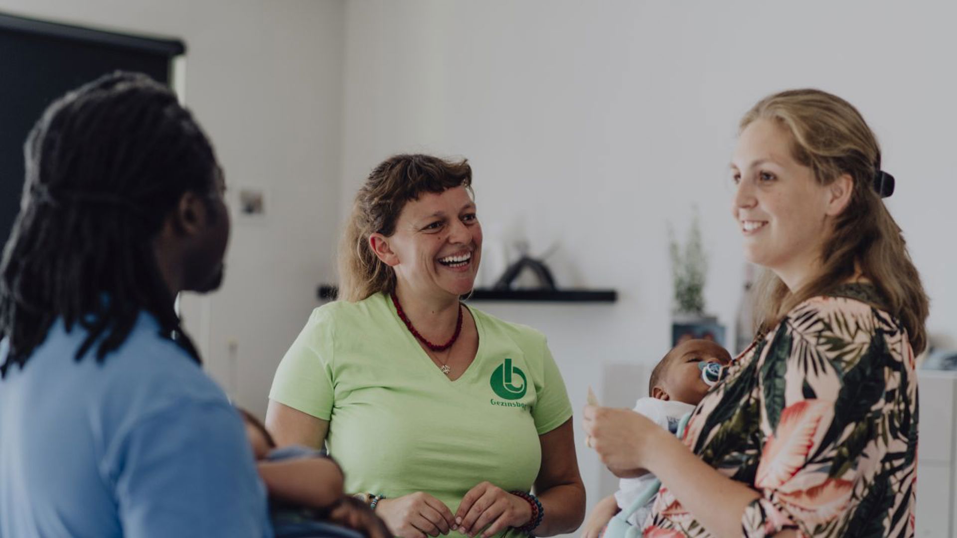 Gezinsbond vrijwilliger praat met gezin met baby's