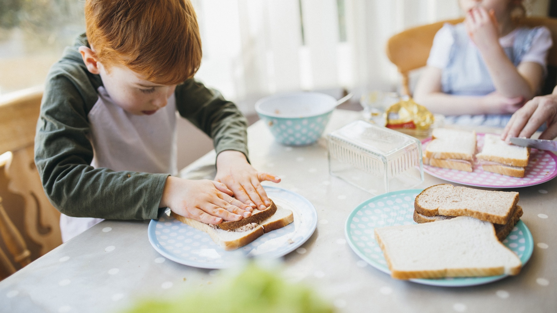 Taken van een babysit - kind smeert boterham