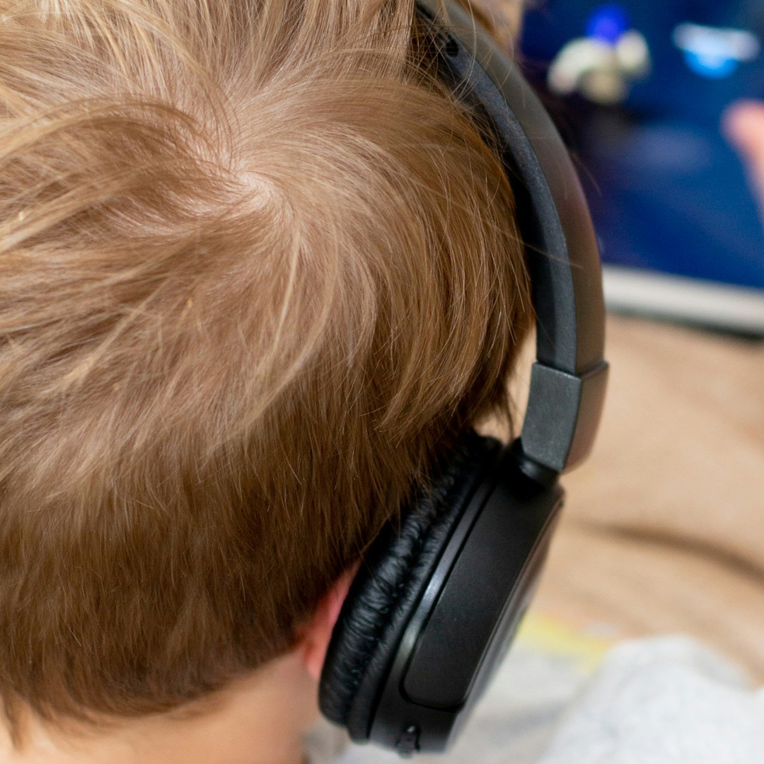 Gamen voor ouders Jongen gamet met koptelefoon