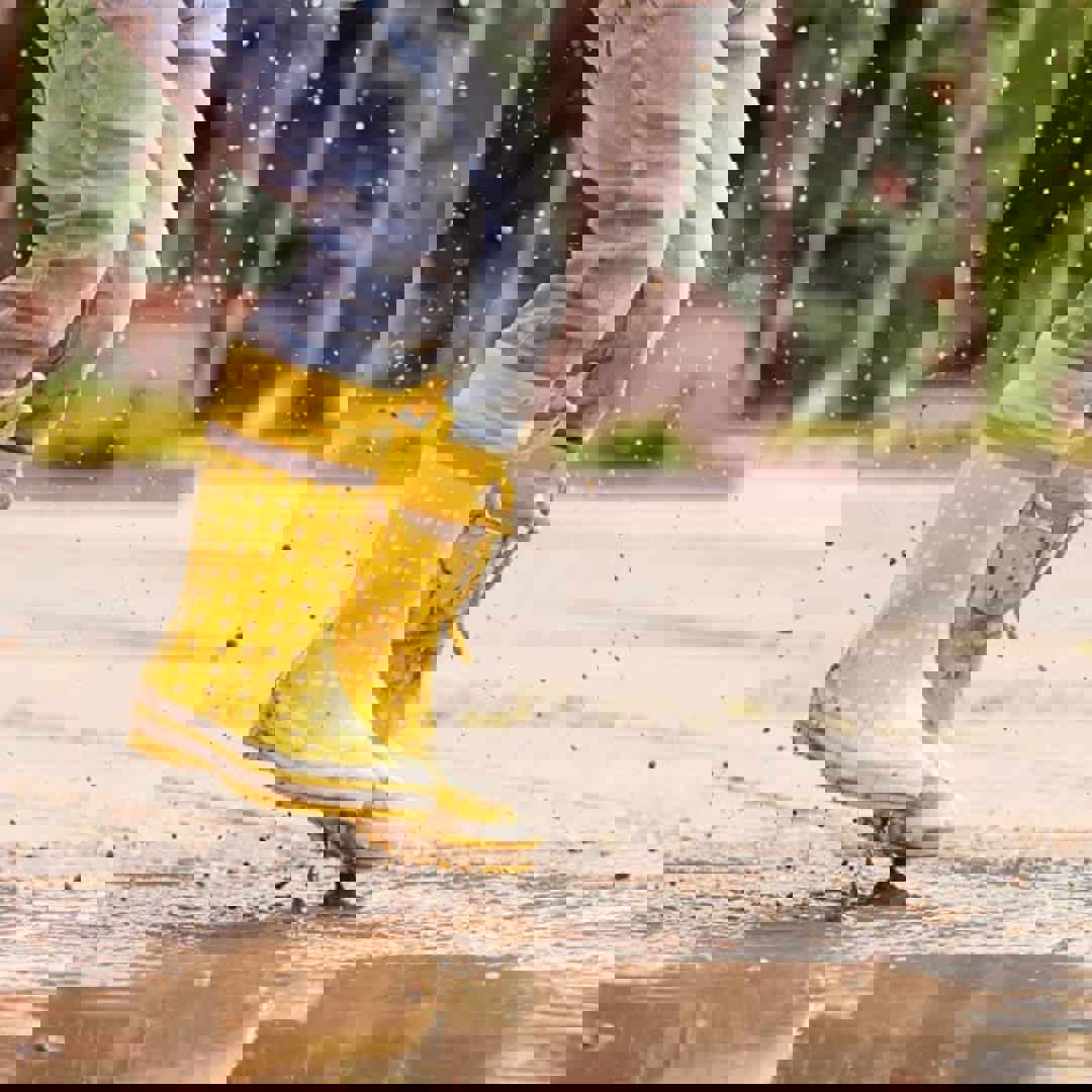 Kind springt met laarzen in een plas