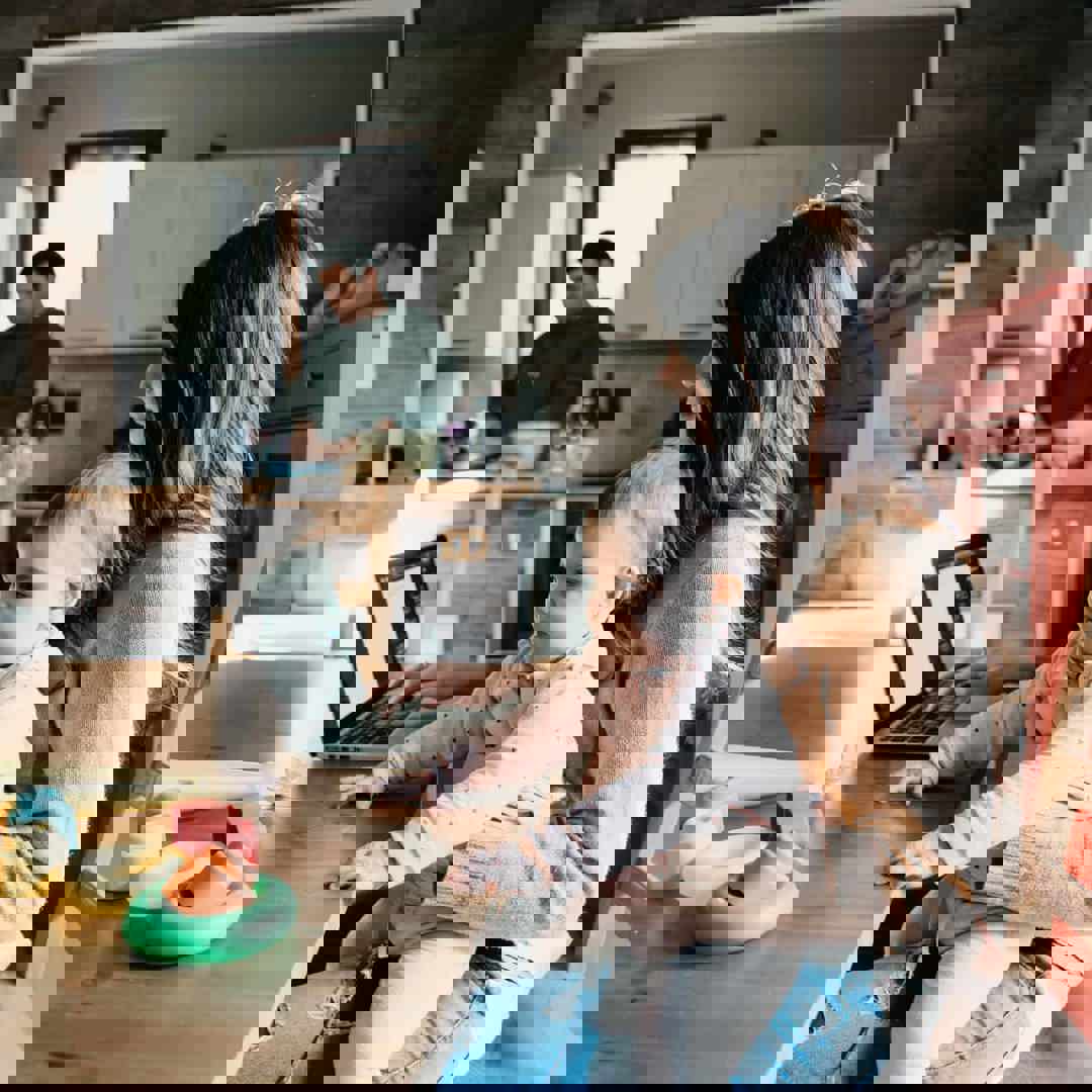 Mama met laptop en baby op schoot Thuiswerken met baby, peuter of kleuter